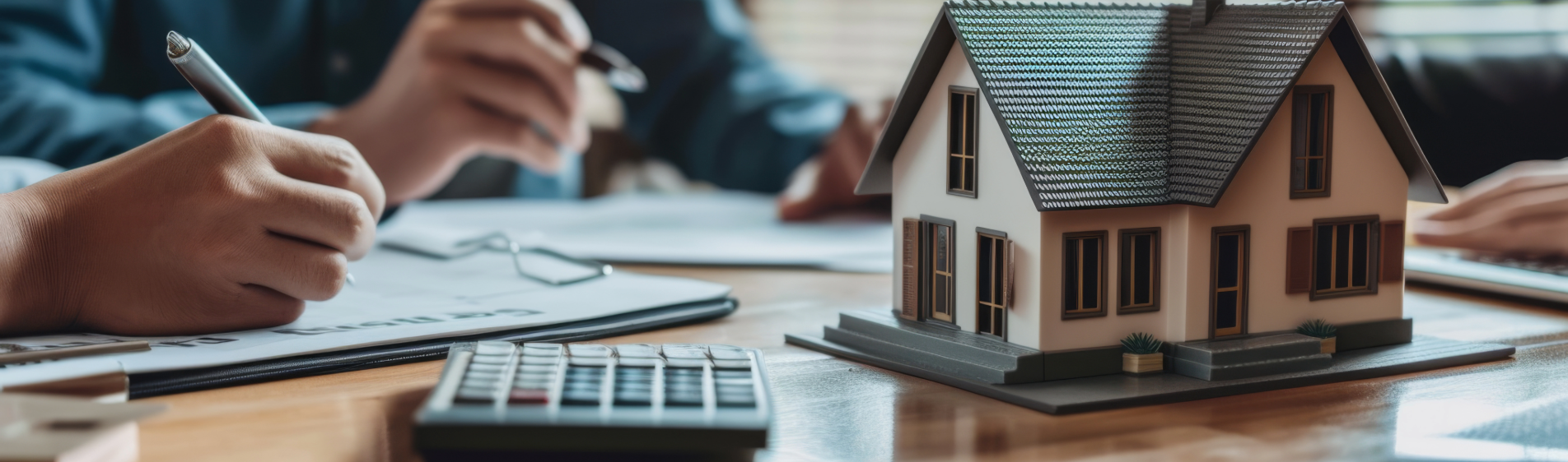 Image of a calculator and a model house on a desk